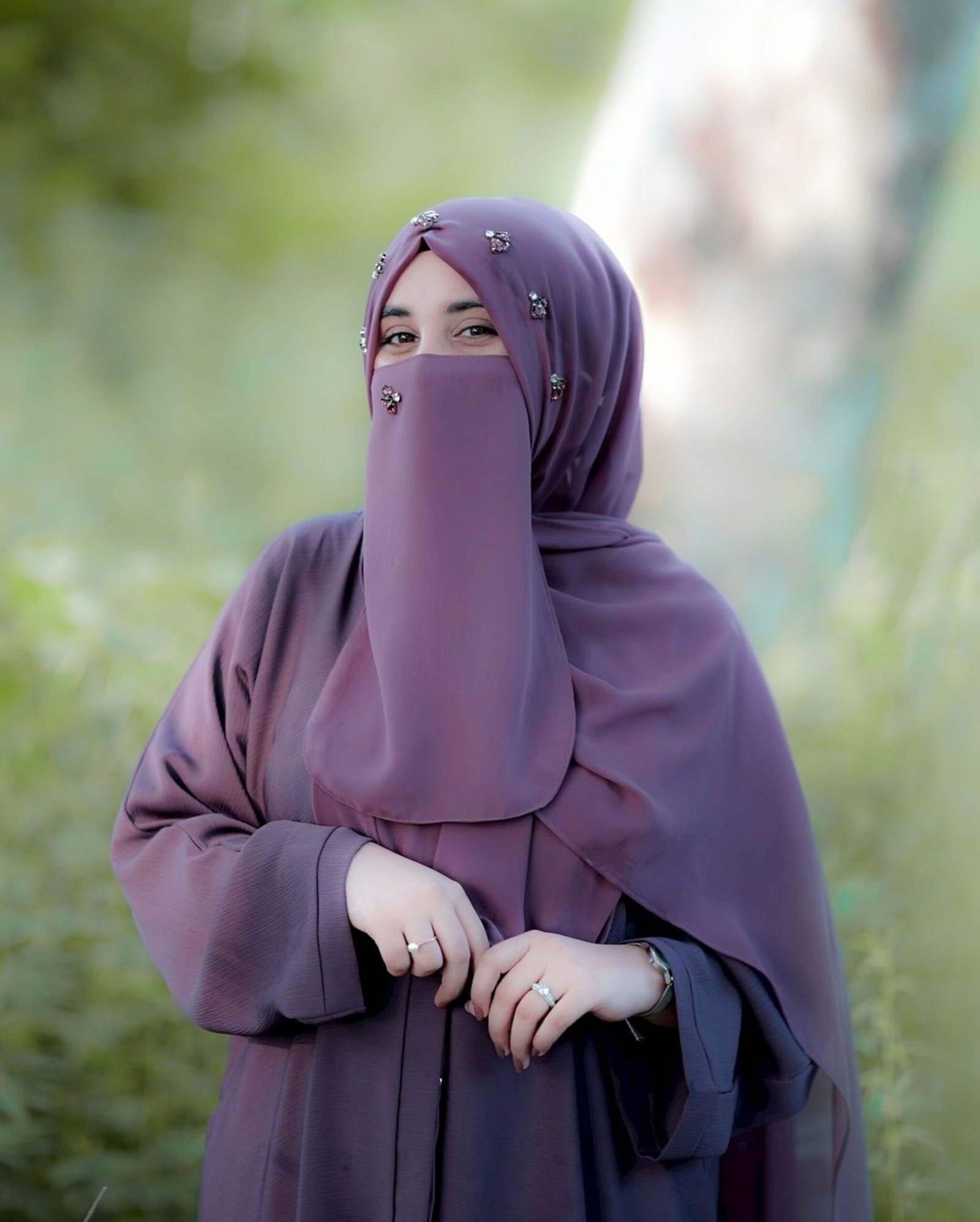 A woman wearing a purple hijab standing in a field